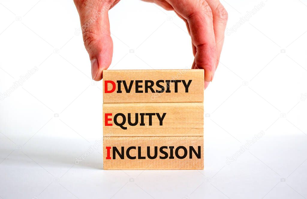 DEI diversity equity inclusion symbol. Concept words DEI diversity equity inclusion on blocks on beautiful white table white background. Businessman hand. Business, diversity equity inclusion concept.