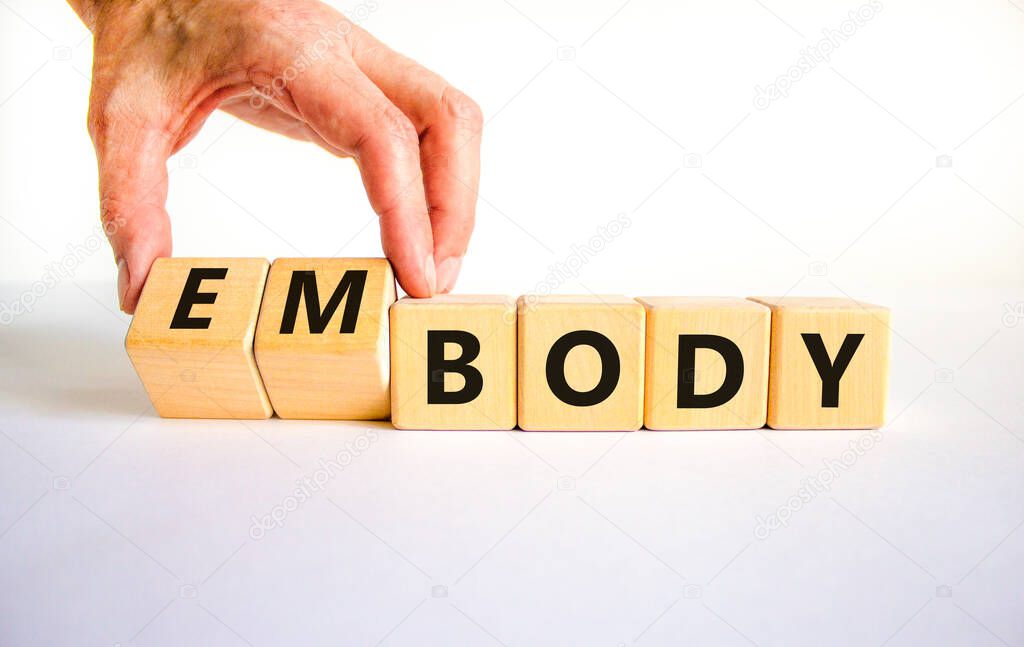Body and embody symbol. Doctor turns wooden cubes and changes the concept word body to embody. Beautiful white table, white background, copy space. Medical, body and embody concept.