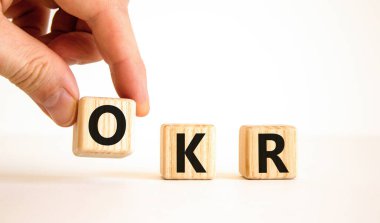 OKR, hedefler ve anahtar sonuç sembolü. OKR hedefleri ve güzel beyaz bir zemin üzerinde tahta küplerin anahtar sonuçları kavramsal sözcüklerdir. İş OKR hedefleri ve temel sonuç kavramı. Boşluğu kopyala.