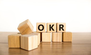 OKR, hedefler ve anahtar sonuç sembolü. OKR hedefleri ve güzel beyaz bir zemin üzerinde tahta küplerin anahtar sonuçları kavramsal sözcüklerdir. İş OKR hedefleri ve temel sonuç kavramı. Boşluğu kopyala.