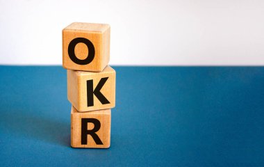 OKR, hedefler ve anahtar sonuç sembolü. OKR hedefleri ve güzel beyaz bir zemin üzerinde tahta küplerin anahtar sonuçları kavramsal sözcüklerdir. İş OKR hedefleri ve temel sonuç kavramı. Boşluğu kopyala.