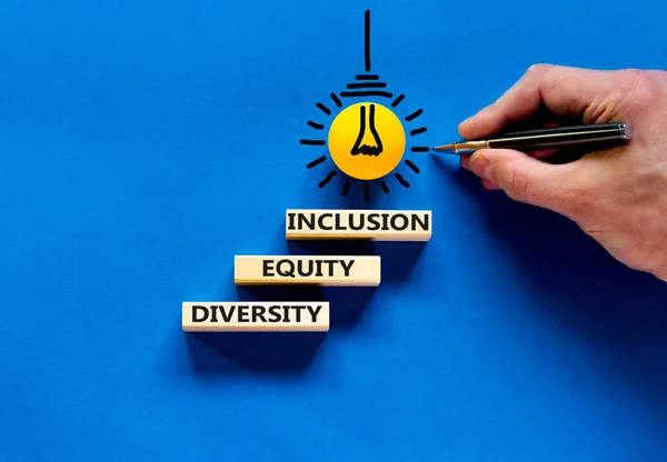 多样性平等包容的象征 概念词多样性公平包括在美丽的蓝色桌子蓝色背景的块上 商人的手 多样性平等包容概念 — 图库照片