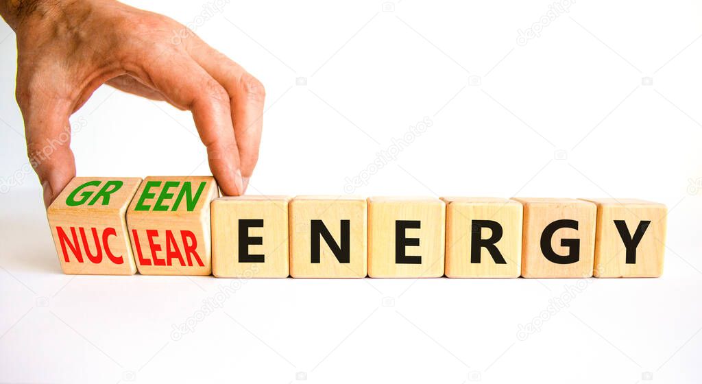 Nuclear or green energy symbol. Businessman turns wooden cubes and changes concept words nuclear energy to green energy. Beautiful white background copy space. Business nuclear green energy concept.