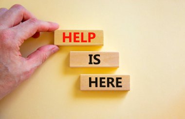 Yardım ve destek sembolü burada. Kavramsal kelimeler Yardım burada tahta bloklarda güzel beyaz masa arka planında. İşadamı eli. İş, destek, yardım kavramı burada. Boşluğu kopyala.