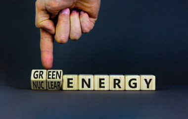 Nükleer ya da yeşil enerji sembolü. İşadamı ahşap küpleri değiştiriyor ve konsepti değiştiriyor. Nükleer enerjiyi yeşil enerjiye çeviriyor. Güzel gri arkaplan kopyalama alanı. Ticari nükleer enerji kavramı.
