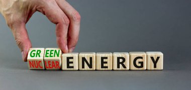 Nükleer ya da yeşil enerji sembolü. İşadamı ahşap küpleri değiştiriyor ve konsepti değiştiriyor. Nükleer enerjiyi yeşil enerjiye çeviriyor. Güzel gri arkaplan kopyalama alanı. Ticari nükleer enerji kavramı.