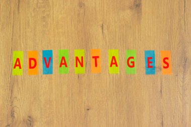 Avantajlar sembolü. Renkli kağıtlarda avantaj kelimesi güzel bir ahşap arka planda. İş ve avantajlar kavramı, kopyalama alanı.
