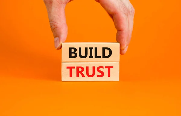 树立信任的象征 概念词在漂亮的橙色桌子背景上的木块上建立信任 商人的手 业务和建立信任概念 复制空间 — 图库照片