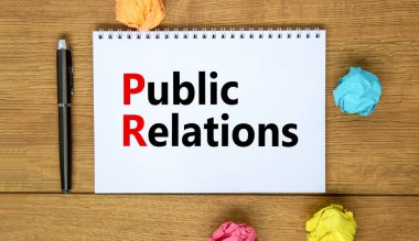 Halkla ilişkiler sembolü. Sözcükler halkla ilişkileri beyaz notaya yansıtır. Metalik kalem. Güzel ahşap arka plan. Uzayı kopyala İş ve Halkla İlişkiler kavramı.