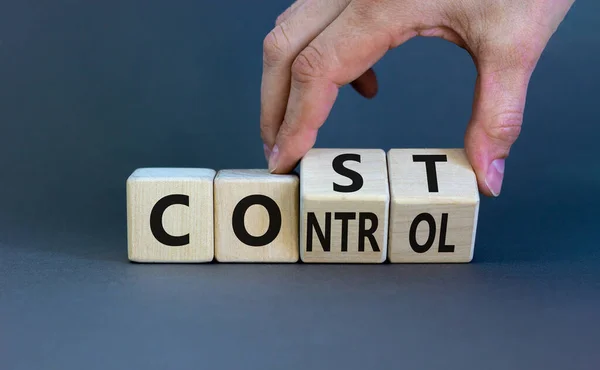 Cost control symbol. Businessman turns wooden cubes and changes the concept word Cost to Control. Beautiful grey table grey background, copy space. Business cost control concept.