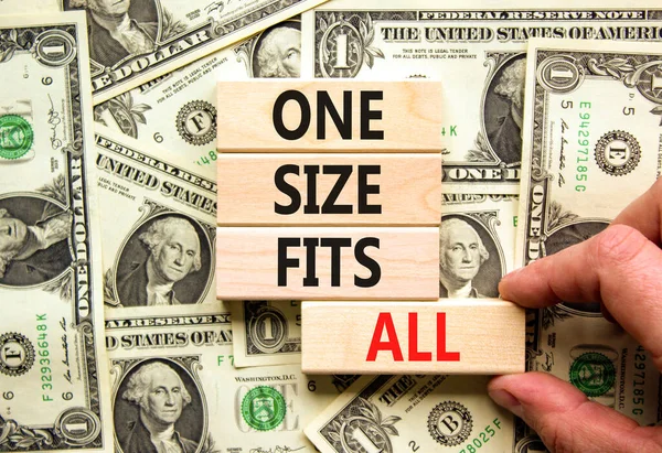 One size fits all symbol. Concept words One size fits all on wooden blocks. Businessman hand. Beautiful background from dollar bills. One size fits all business concept. Copy space.