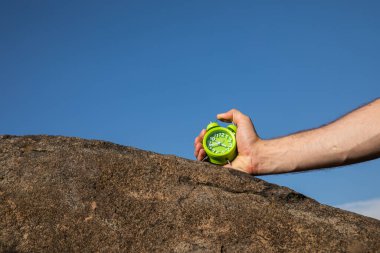 Mavi arkaplanda yeşil alarmlı saati tutan kadın, görüntüyü kapat.