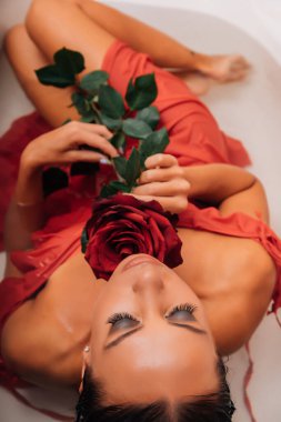 Lüks kaplıca kadını. Zarif gözler ipek tenli alımlı kız gül yapraklarının arasında uzanmış su banyosunda eğleniyor. Kadın sütle dolu bir sağlık banyosu yapıyor..