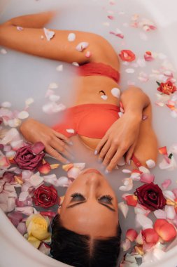 Lüks kaplıca kadını. Zarif gözler ipek tenli alımlı kız gül yapraklarının arasında uzanmış su banyosunda eğleniyor. Kadın sütle dolu bir sağlık banyosu yapıyor..