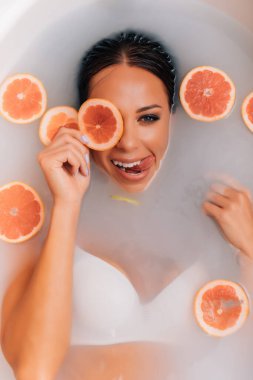 Lüks kaplıca kadını. Zarif gözler ipek tenli alımlı kız gül yapraklarının arasında uzanmış su banyosunda eğleniyor. Kadın sütle dolu bir sağlık banyosu yapıyor..