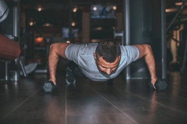 Delikanlı vücut geliştirici koyu renk spor salonunda halterle egzersiz yapıyor..