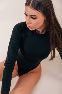 Çekici bronz tenli esmer, siyah iç çamaşırlı. Yerde otur, tüm vücudunu çek, az miktarda tahıl ekle, stüdyo çekimi yap..