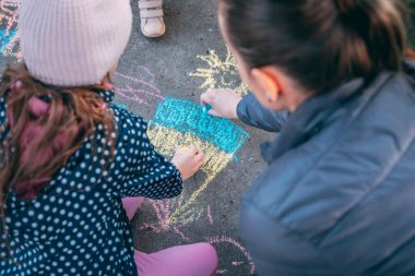 Çocuk asfalta tebeşirle Ukrayna bayrağı çekiyor. Seçici odaklanma. Onlar savaş istemiyor. Ukraynalı mülteciler.