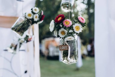 Düğün süslemeleri. Minik vazolar ve tavandan sarkan çiçek buketleri şeklinde orijinal düğün çiçekleri..