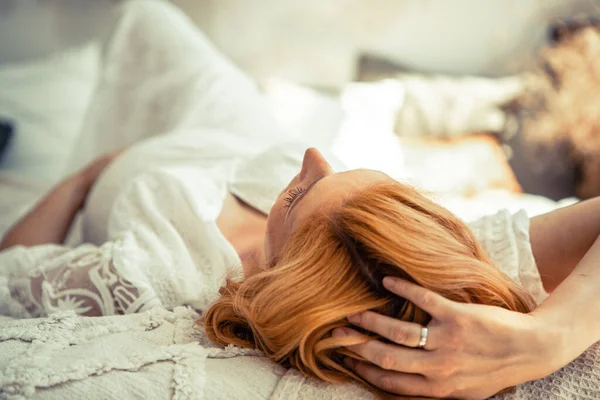 Avrupalı hamile kadın evdeki kanepede dinleniyor. Hamile kızıl saçlı kadın evde rahat bir yatakta uzanıyor..