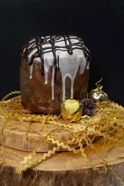 Ahşap bir masada panettone, siyah bir zemin, Noel süsleriyle çevrili.