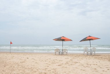 Güneşli bir günde plaj sandalyeleri ve şemsiyesi olan güzel bir manzara..