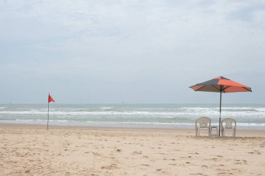 Güneşli bir günde plaj sandalyesi ve şemsiyesi olan güzel bir manzara..