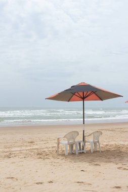 Güneşli bir günde plaj sandalyesi ve şemsiyesi olan güzel bir manzara..
