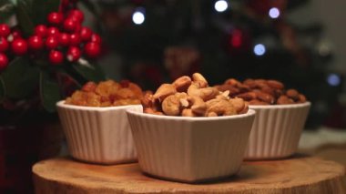 Tahta bir masanın üzerinde noel ışığı olan üç kase ceviz.