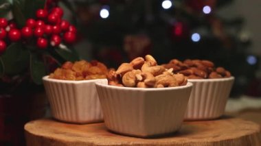 Tahta bir masanın üzerinde noel ışığı olan üç kase ceviz.