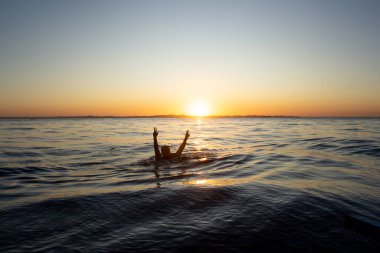 a man swimming at the sea in a sunset