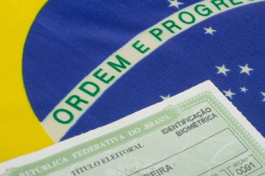 hand holding brazilian election document  near brazilian flag