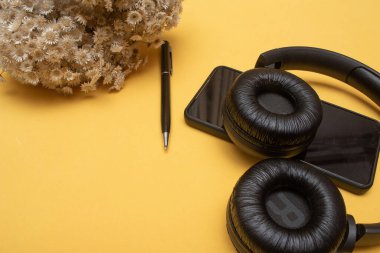cellphone and headset on table on yellow background - office