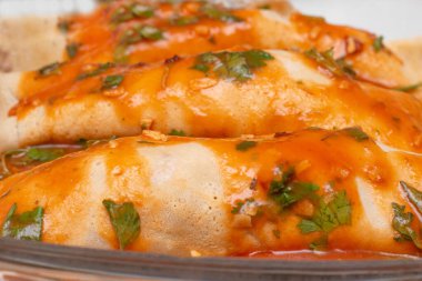 Domates soslu tavuklu gözleme. Cam kasede fesleğen yapraklarıyla dolu.