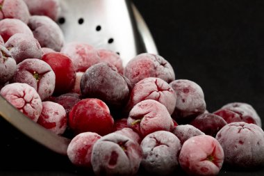 Bir kase dolusu taze aserola ve siyah arkaplan.