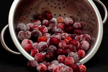 Bir kase dolusu taze aserola ve siyah arkaplan.