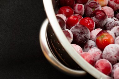 Bir kase dolusu taze aserola ve siyah arkaplan.