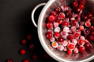 Bir kase dolusu taze aserola ve siyah arkaplan.