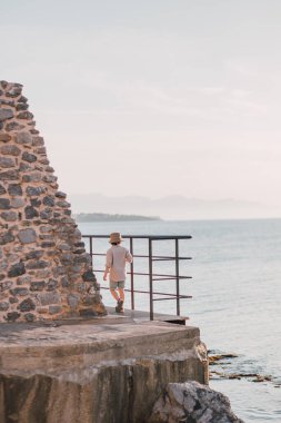 Sıcak bir akşam ışığında uçurumda yürüyen bir çocukla manzaralı bir deniz manzarası. Yaşam tarzı imajı, yaz tatili konsepti. Boşluğu kopyala
