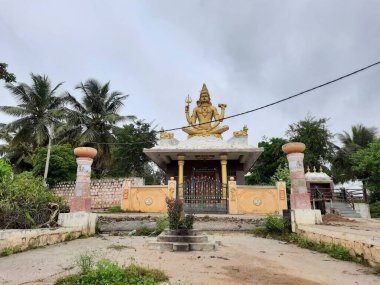 Channapatna, Karnataka, Hindistan-Aug 15 2021: Güzel eski Sri Arkeshwara Tapınağı Altın Renkli Shiva heykelinin yakın çekimi, Bevoor tapınağının tepesinde, Gölet 'in yanında