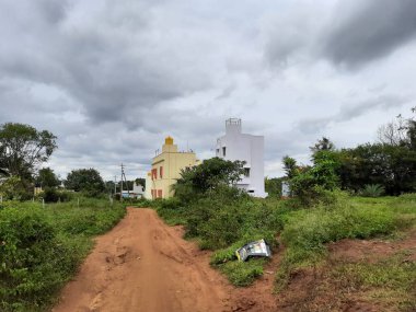 Güzel Hint kırsalına ya da kırsal kesimine yakın, doğada binaları olan çamurlu yol.