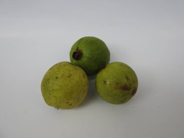 Beyaz arkaplanda izole edilmiş üç yeşil ve sarı guava meyvesi.