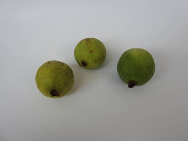 Beyaz arkaplanda izole edilmiş üç yeşil ve sarı guava meyvesi.