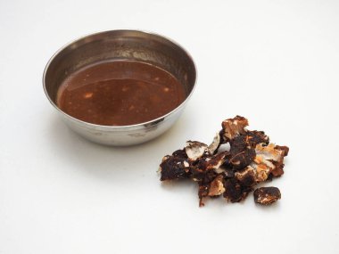 Beyaz arka planda izole edilmiş çelik bir kasede Hint Tamarind meyvesi ve meyve suyu yığını.