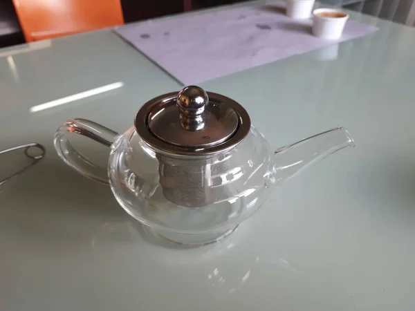 隔离在桌上的人造玻璃瓶和金属茶叶滤清器 — 图库照片