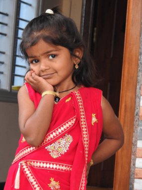 Bangalore, Karnataka, Hindistan-15 Ocak 2022: Geleneksel olarak Makara Sankranti veya Pongal Prasada 'yı komşulara dağıtmak için giydirilmiş güzel Hintli kız çocuğuna yakın çekim.