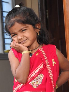 Bangalore, Karnataka, Hindistan-15 Ocak 2022: Geleneksel olarak Makara Sankranti veya Pongal Prasada 'yı komşulara dağıtmak için giydirilmiş güzel Hintli kız çocuğuna yakın çekim.