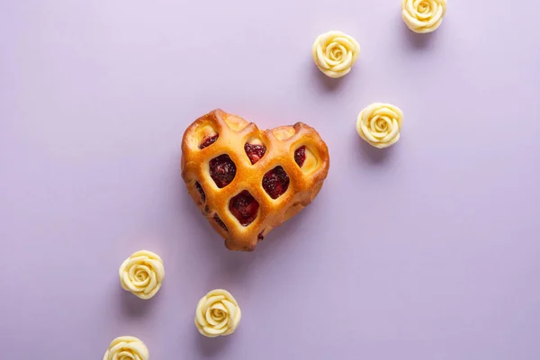 Valentines Day concept. Heart-shaped bun with lattice crust and berry jam on a lilac background with white chocolate roses. Flat lay, copy space. — Stock Photo, Image