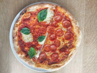 Yarım salamlı pizza ve yarım mozzarella soslu Margherita pizza, domates sosu ve fesleğen. Taze ve çıtır. İtalyan spesiyali. Salamlı pizza ve mozzarella soslu Margherita pizza, domates sosu ve fesleğen. Fırından yeni çıkmış taze ve çıtır çıtır..