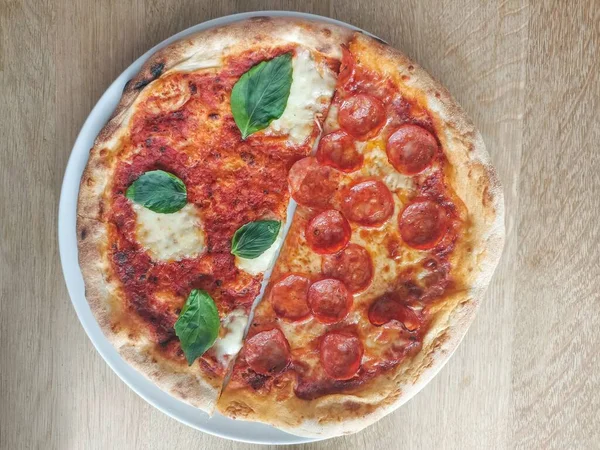 Yarım salamlı pizza ve yarım mozzarella soslu Margherita pizza, domates sosu ve fesleğen. Taze ve çıtır. İtalyan spesiyali. Salamlı pizza ve mozzarella soslu Margherita pizza, domates sosu ve fesleğen. Fırından yeni çıkmış taze ve çıtır çıtır..